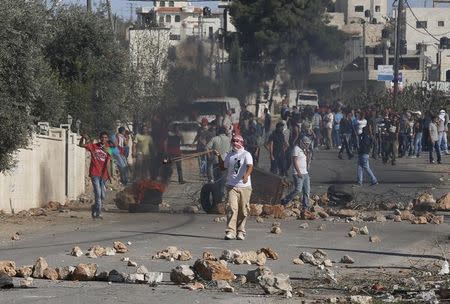 Palestinian protesters use slingshots to hurl stones toward Israeli troops during clashes following the funeral of Palestinian-American youth Orwah Hammad, whom medics said was killed by Israeli forces, in the West Bank village of Silwad near Ramallah October 26, 2014. REUTERS/Ammar Awad