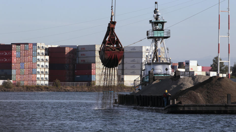 FILE - Shipping containers line one side of the Duwamish River and barges with gravel line another, Sept. 28, 2011, in Seattle. Ending an eight-year legal battle, chemical giant Monsanto has agreed to a $160-million settlement with Seattle for its part in polluting the Lower Duwamish River with toxins that posed a threat to humans and wildlife, the city attorney's office said in a press release Thursday, July 25, 2024. (AP Photo/Elaine Thompson, File)