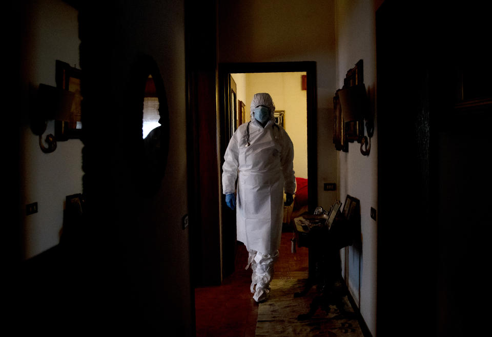 Doctor Luigi Cavanna wears protective gear as he walks in a corridor to leave after visiting COVID-19 patient Maria Teresa Orsi in her home, in Monticelli d'Ongina, near Piacenza, Italy, Wednesday, Dec. 2, 2020. (AP Photo/Antonio Calanni)