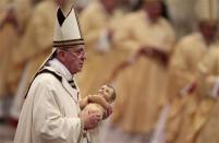 Pope Francis holds the baby Jesus statue at the end of the Christmas night mass in the Saint Peter's Basilica at the Vatican December 24, 2013. REUTERS/Tony Gentile