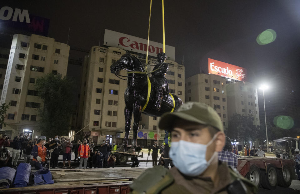 Cranes remove the statue of Gen. Manuel Baquedano, a Chilean military officer and politician, at Plaza Italia Friday, March 12, 2021, in Santiago, Chile. The statue located at the epicenter of the protests in Chile was removed early Friday be order of the National Monuments Council to be restored. (AP Photo/Esteban Felix)