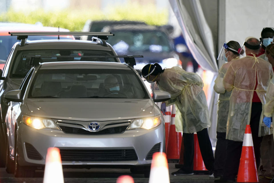 FILE - In this Jan. 6, 2021, file photo, health care workers prepare to inoculate a driver at a COVID-19 testing site, outside Hard Rock Stadium in Miami Gardens, Fla. Coronavirus deaths and cases per day in the U.S. dropped markedly over the past couple of weeks but are still running at alarmingly high levels, and the effort to snuff out COVID-19 is becoming an ever more urgent race between the vaccine and the mutating virus. (AP Photo/Wilfredo Lee, File)