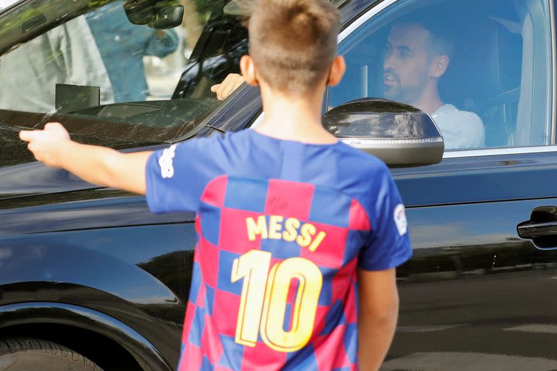 Foto del domingo de un niño con una camiseta del Barcelona de Lionel Messi junto al auto de Sergio Busquets a su llegada para hacerse los controles de coronavirus previos al inicio de la pretemporada