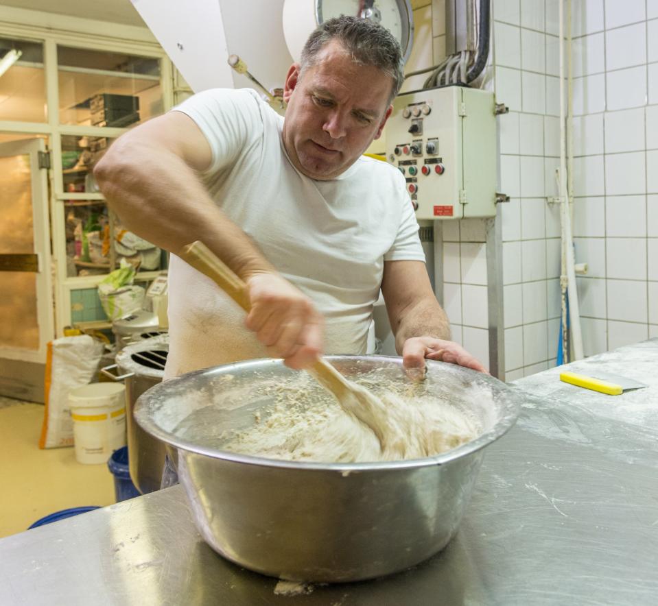 A man mixing dough in a large bowl.