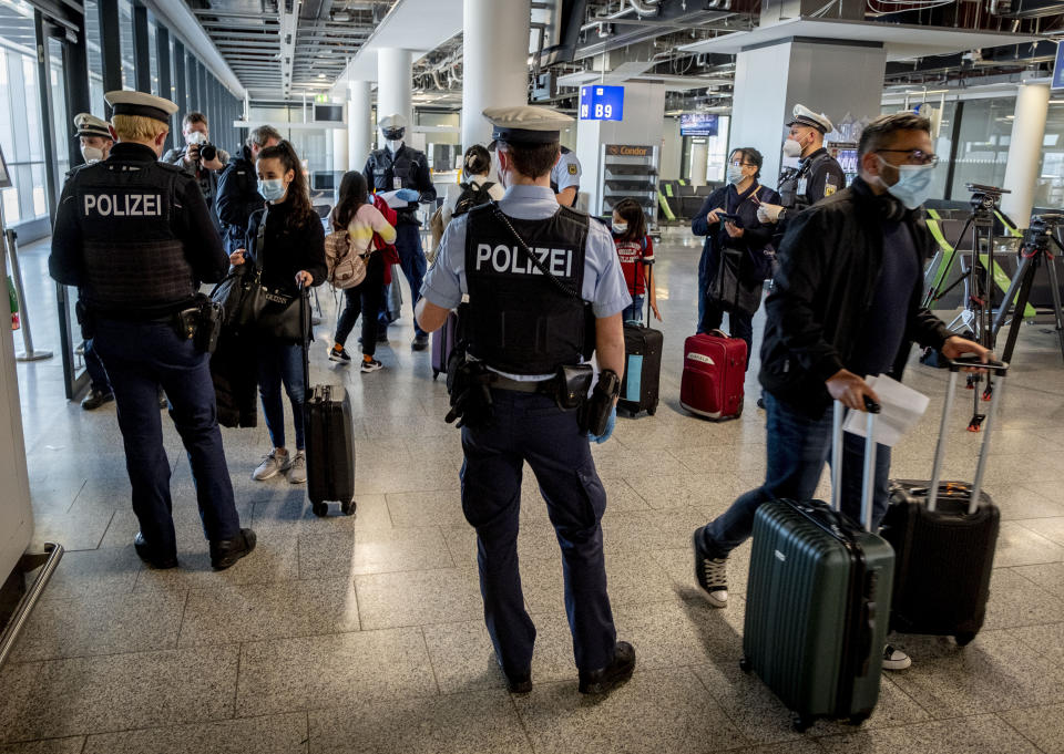 FILE - In this March 30, 2021, file photo, German federal police officers check passengers arriving from Palma de Mallorca for a negative Corona test as they arrive at the airport in Frankfurt, Germany. Germany will require people entering the country who haven’t been vaccinated or recently recovered from COVID-19 to show a negative test result starting from Sunday. (AP Photo/Michael Probst, File)