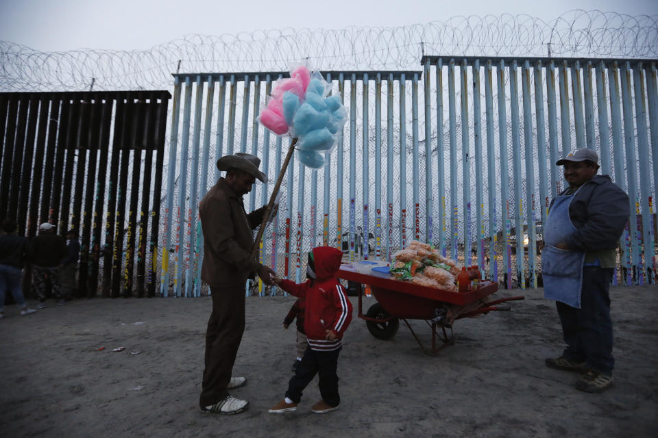 A Honduran migrant boy tries to buy cotton candy from a vendor, but doesn't have enough money, as migrants visit the U.S. border wall to look for opportunities to cross, at the beach in Tijuana, Mexico, on Sunday, Dec. 9, 2018. Discouraged by the long wait to apply for asylum through official ports of entry, many Central American migrants from recent caravans are choosing to cross the U.S. border wall illegally and hand themselves in to Border Patrol agents to request asylum. (AP Photo/Rebecca Blackwell)