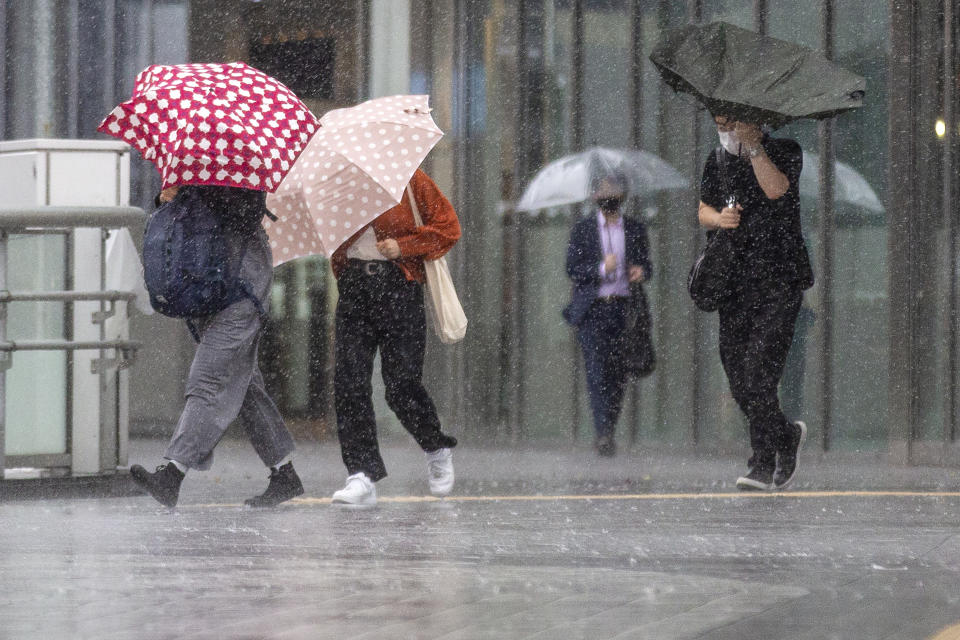 People struggle with rain and strong wind as Typhoon Mindulle travels off the coast of Japan Friday, Oct. 1, 2021, in Tokyo. (AP Photo/Kiichiro Sato)