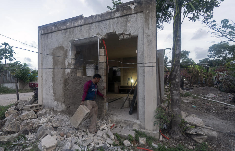 Un residente del barrio 2 de Octubre lleva un bloque de cemento a la casa que se está construyendo en ese asentamiento surgido en terrenos ocupados en Tulum (México) el 4 de agosto del 2022. (AP Photo/Eduardo Verdugo)