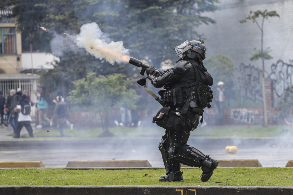 A police officer fires tear gas at anti-government protesters in Bogota, Colombia, Thursday, Nov. 21, 2019. Colombia's main union groups and student activists called for a strike to protest the economic policies of Colombian President Ivan Duque government and a long list of grievances. (AP Photo/Ivan Valencia)