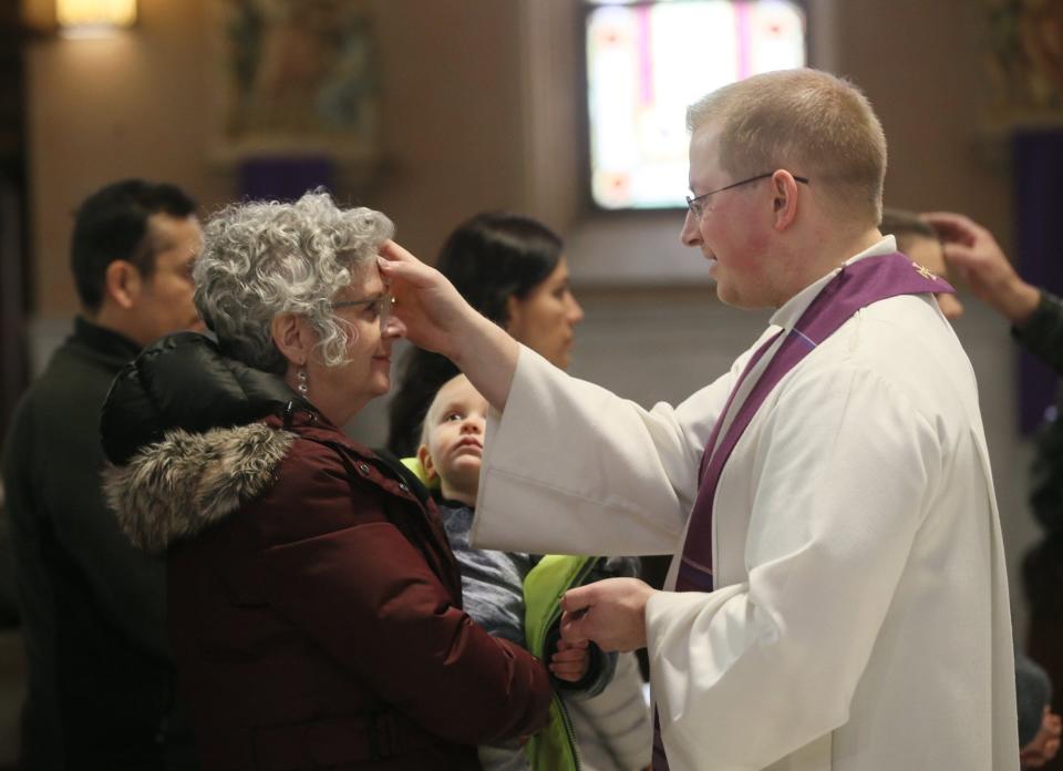 Quinn Adkins, 18-months, watches as Father Chris Zerucha makes the sign of the cross in ashes on the forehead of his grandmother Lynda Kellackey of Akron during an Ashes only prayer service at St. Bernard Catholic Church on Wednesday March 6, 2019 in Akron, Ohio. (Beacon Journal file)