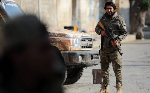 A Turkish-backed Syrian fighter stands at attention in the Syrian border town of Tal Abyad  - Credit: BAKR ALKASEM/AFP via Getty Images