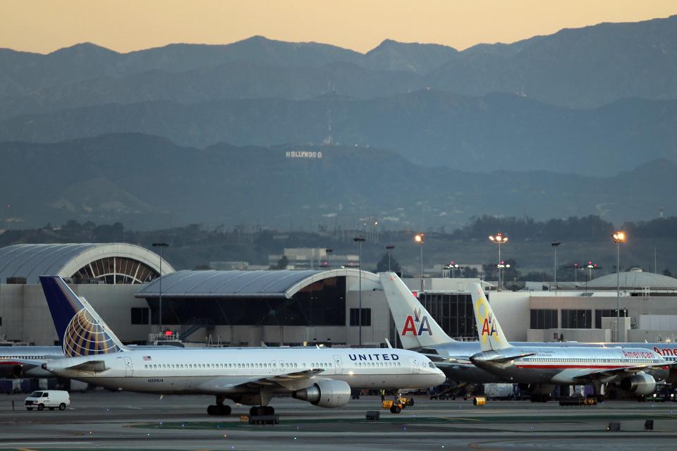 A United Boeing 777 takes off with the Hollywood sign in the distance at Los Angeles International Airport (LAX) on January 17, 2013 in Los Angeles, California.