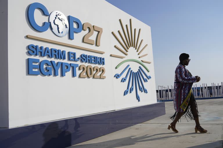 Una mujer pasa junto a un cartel con el logo de la cumbre climática de Naciones Unidas, COP27, el 16 de noviembre de 2022, en Sharm el-Sheikh, Egipto. (AP Foto/Peter Dejong)