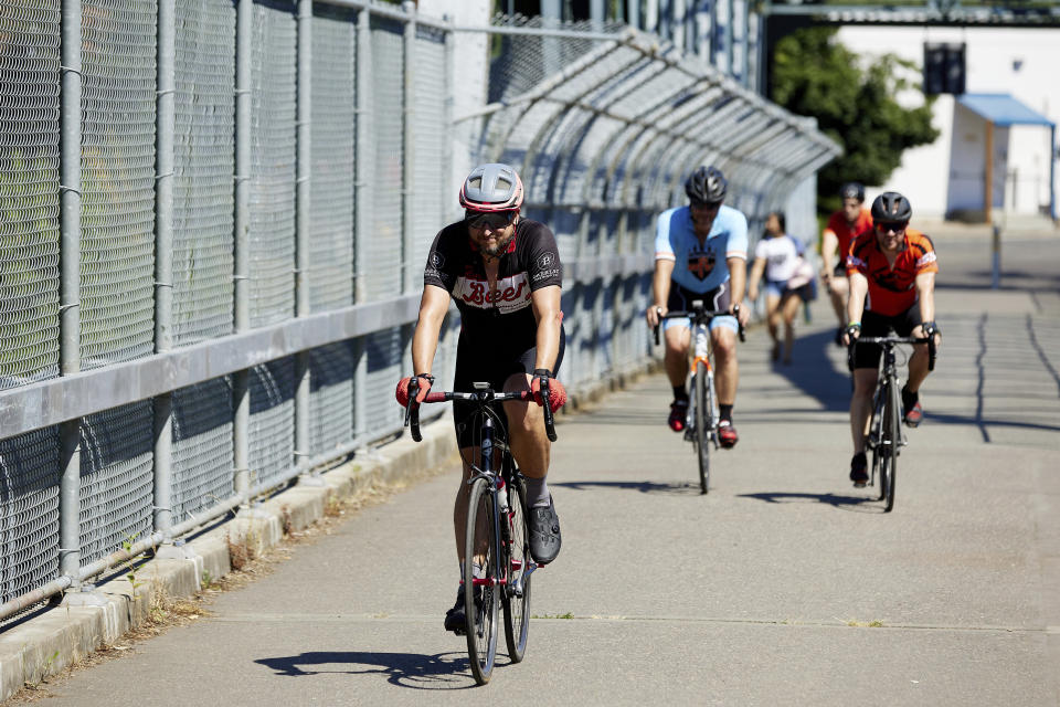 Bicyclists ride across a pedestrian bridge in the morning to escape from the heat during a record setting heat wave in Portland, Ore., Sunday, June 27, 2021. Yesterday set a record high for the day with more records expected today. (AP Photo/Craig Mitchelldyer)