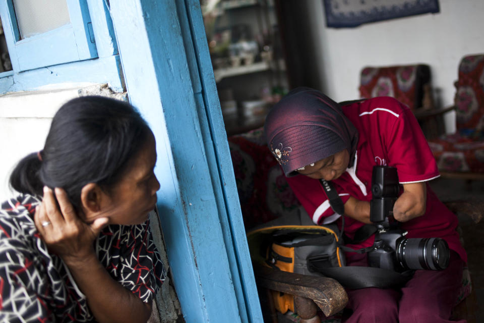 PURWOREJO, INDONESIA - MARCH 14: Armless professional photographer Rusidah, 44, prepares camera before taking a customer's portrait on March 14, 2012 in Purworejo, Indonesia. Rusidah shoots weddings and parties and has a small studio at home in the village of Botorejo, Bayan District, Purworejo, Central Java where her husband and son also reside. She has been in the photography business for nearly 20 years. (Photo by Ulet Ifansasti/Getty Images)