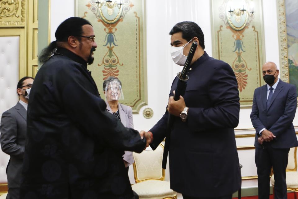 En esta imagen proporcionada por la oficina de prensa de Miraflores, el actor Steven Seagal, a la izquierda, y el presidente venezolano Nicolás Maduro se dan la mano luego que Seagal le obsequió a Maduro una espada samurai, en el palacio presidencial en Caracas, Venezuela, el martes 4 de mayo de 2021. (Oficina de prensa de Miraflores vía AP)