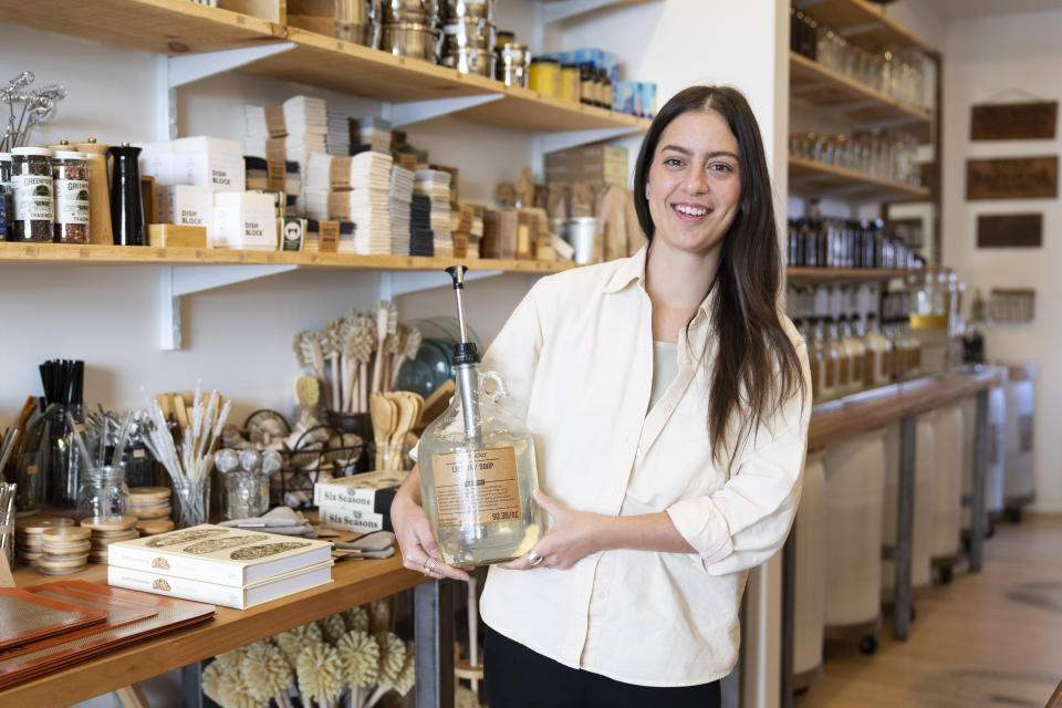 File - Emily Rodia, owner of Good Buy Supply, holds concentrated laundry soap that customers can pump into their own refillable containers at her store in Philadelphia. At the dawn of 2024, also known as New Year's resolution season, there are lots of small, easily achievable ways to lead more climate friendly lives. (AP Photo/Matt Rourke, File)