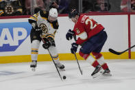 Boston Bruins defenseman Dmitry Orlov (81) and Florida Panthers center Eetu Luostarinen (27) go after the puck during the third period of Game 4 of an NHL hockey Stanley Cup first-round playoff series, Sunday, April 23, 2023, in Sunrise, Fla. (AP Photo/Marta Lavandier)