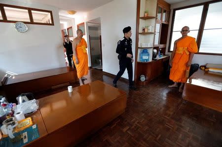 A policeman and Buddhist monks search for a fugitive Buddhist monk inside Dhammakaya temple in Pathum Thani province, Thailand February 17, 2017. REUTERS/Chaiwat Subprasom