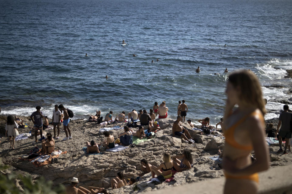 FILE - In this, July 25, 2020, file photo, people enjoy the sun at the Malmousque Beach in Marseille, in southern France. An outbreak among 18- to 25-year-olds at a seaside resort on the Brittany coast is crystallizing fears that the virus is flaring again in France, on the back of vacationers throwing COVID-19 caution to the summer winds. (AP Photo/Daniel Cole, File)