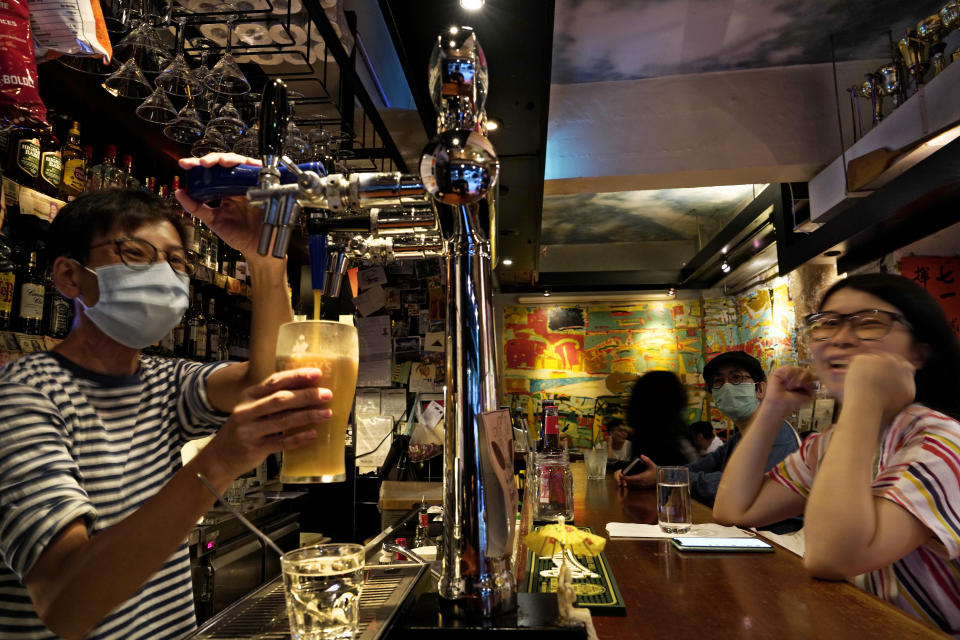 In this Oct. 7, 2020 photo, an employee serves a beer to a customer at Club 71 in Hong Kong. The bar known as a gathering place for pro-democracy activists and intellectuals is closing. For years, the storied bar has served as a watering hole for the city’s pro-democracy activists and intellectuals, who could freely engage in discussions over a round of beer or two. (AP Photo/Vincent Yu)