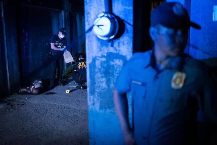 Police gather evidence during a shooting by unidentified gunmen in Manila.