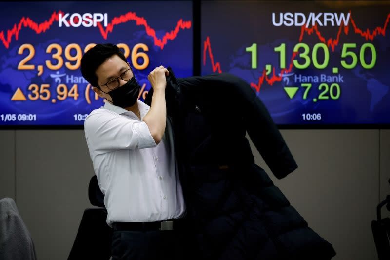 FILE PHOTO: A currency dealer walks past electronic boards showing the Korea Composite Stock Price Index (KOSPI) and the exchange rate between the U.S. dollar and South Korean won at a dealing room of a bank, in Seoul, South Korea, November 5, 2020.    REUTERS/Kim Hong-Ji/File Photo