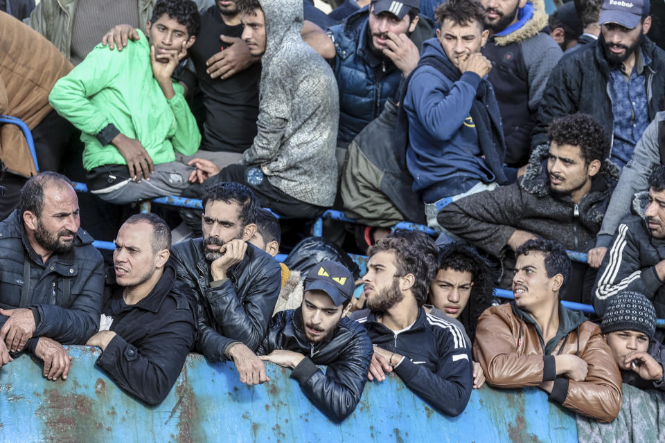 Migrants look out of a fishing boat docked at the port of Palaiochora in southeastern Crete, Greece, after its arrival, on Tuesday, Nov. 22, 2022 . Greek authorities say a fishing boat crammed with hundreds of migrants that lost steering and had been drifting in the Mediterranean south of the Greek island of Crete has been successfully towed to port. There were no immediate reports of any injuries or missing people. (Stefanos Rapanis/Eurokinissi via AP)