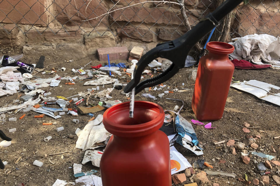 FILE - In this Aug. 9, 2019, file photo, a drug syringe found behind a vacant property in northeast Albuquerque, N.M., is placed into a container, as crews attempt to clear the lot of needles and other heroin paraphernalia. Police in Oregon can no longer arrest someone for possession of small amounts of heroin, methamphetamine and other hard drugs as a ballot measure that decriminalized them took effect on Monday, Feb. 1, 2021. (AP Photo/Mary Hudetz, File)