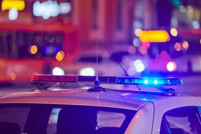 The lights atop a police vehicle flash against the blurred image of other cars and buses in the background.