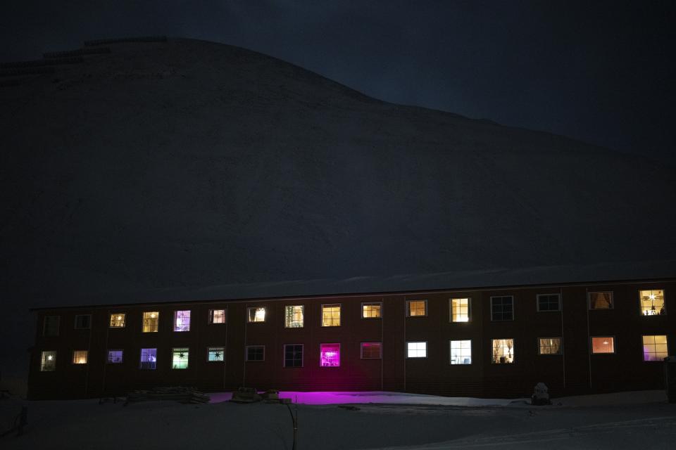 Ventanas iluminan la noche polar en Longyearbyen, Noruega, el viernes 6 de enero de 2023. Tan cerca del Polo Norte, el sol está al menos seis grados bajo el horizonte de mediados de noviembre hasta finales de enero. (AP Foto/Daniel Cole)