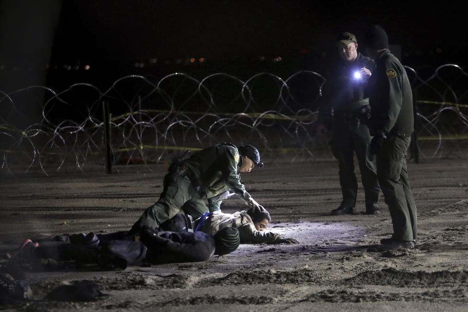 A U.S. Border Patrol agent pats down Honduran migrants after they crossed onto U.S territory from Tijuana, Mexico, on Friday, Nov. 30, 2018. Thousands of migrants who traveled via a caravan want to seek asylum in the U.S., but inspectors at the San Ysidro border crossing are processing about 100 claims a day, meaning they will likely have to wait weeks or months. (AP Photo/Felix Marquez)