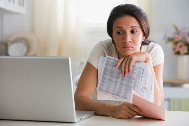 BEAWA3 Worried woman holding bills and looking at laptop