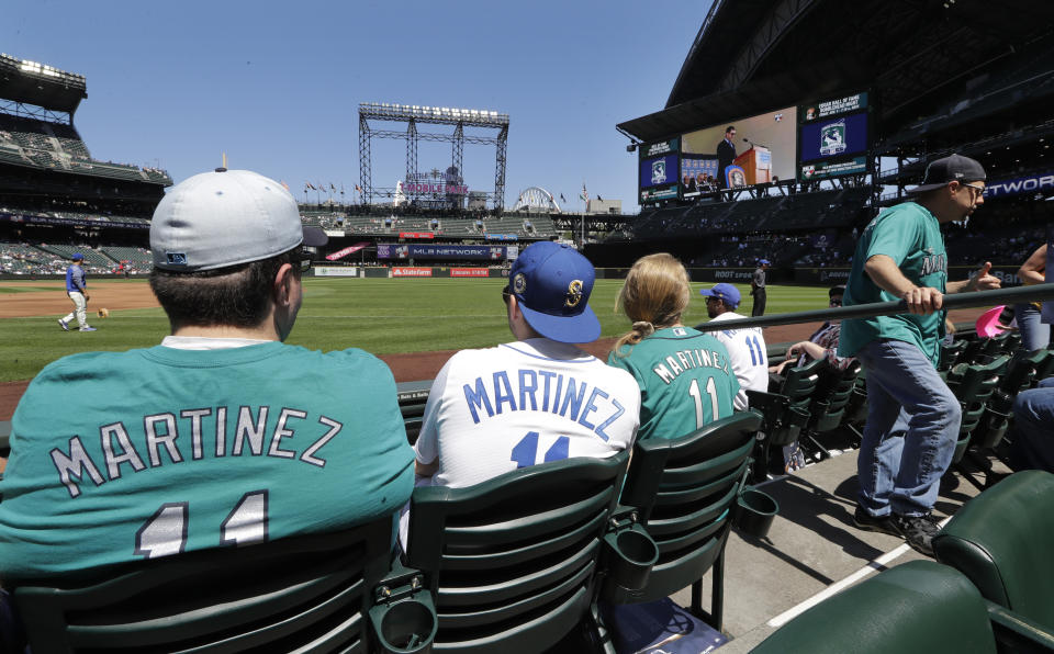 Seattle Mariners fans watch a monitor showing former Mariners' designated hitter Edgar Martinez as he speaks during his Hall of Fame induction ceremony before a baseball game Sunday, July 21, 2019, in Seattle. (AP Photo/Elaine Thompson)