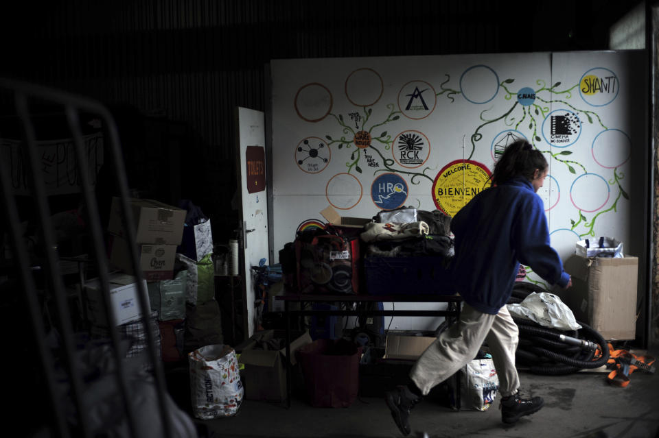 A volunteer runs in a warehouse where associations helping migrants are gathered, in Calais, northern France, Saturday, Nov. 27, 2021. At the makeshift camps outside Calais, migrants are digging in, waiting for the chance to make a dash across the English Channel despite the news that at least 27 people died this week when their boat sank a few miles from the French coast. (AP Photo/Rafael Yaghobzadeh)