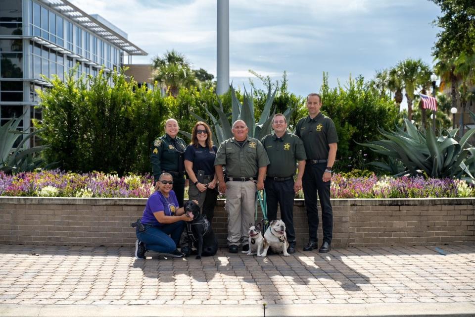 From left to right Corporal Erica Rodriguez (kneeling), Segreant Kelly Stone, Erica Stamborski (Community Services Division), Corporal Robert Bedgood, Chaplain Josh Douglas, and Chaplain Jason Low pose with therapy dogs Jetty, Eve and Mia.