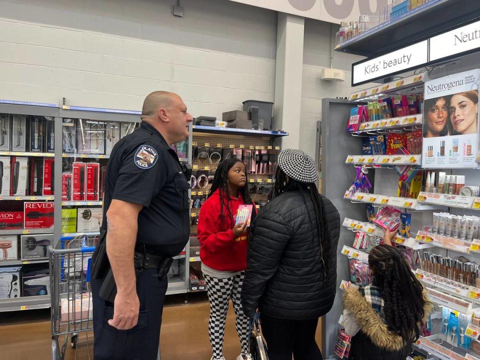 Officer Bryan Jaeger, peers at lipgloss in the makeup aisle, with Micah, 12, and her mother, Spencer Johnson.
