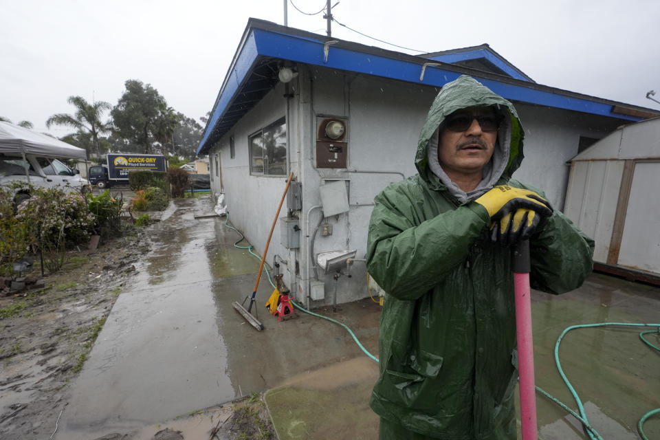 Ruben Gomez pauses as he digs away some of the mud and flood debris that engulfed his parents' home in the previous rainstorm as more rain falls, Thursday, Feb. 1, 2024, in San Diego. Gomez has spent all of his time since the Jan. 22 storm shuttling between caring for his parents who were rescued by boat and later hospitalized that day, and trying to salvage what he can from the flooded home. Now, with more rain coming, Gomez worries the floodwaters may rise again in his parents' neighborhood. (AP Photo/Gregory Bull)