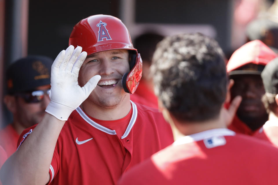 FILE - In this Feb. 25, 2020, file photo, Los Angeles Angels' Mike Trout smiles after scoring during the first inning of a spring training baseball game against the Cincinnati Reds, in Tempe, Ariz. Mike Trout hit two home runs off Zack Greinke and scored four times to help the Los Angeles Angels beat the Houston Astros 9-6 on opening day. Alas, the game was played on a computer, not on the field. But as fans of the Strat-O-Matic board game can attest, make-believe box scores can be fun too. (AP Photo/Darron Cummings, File)