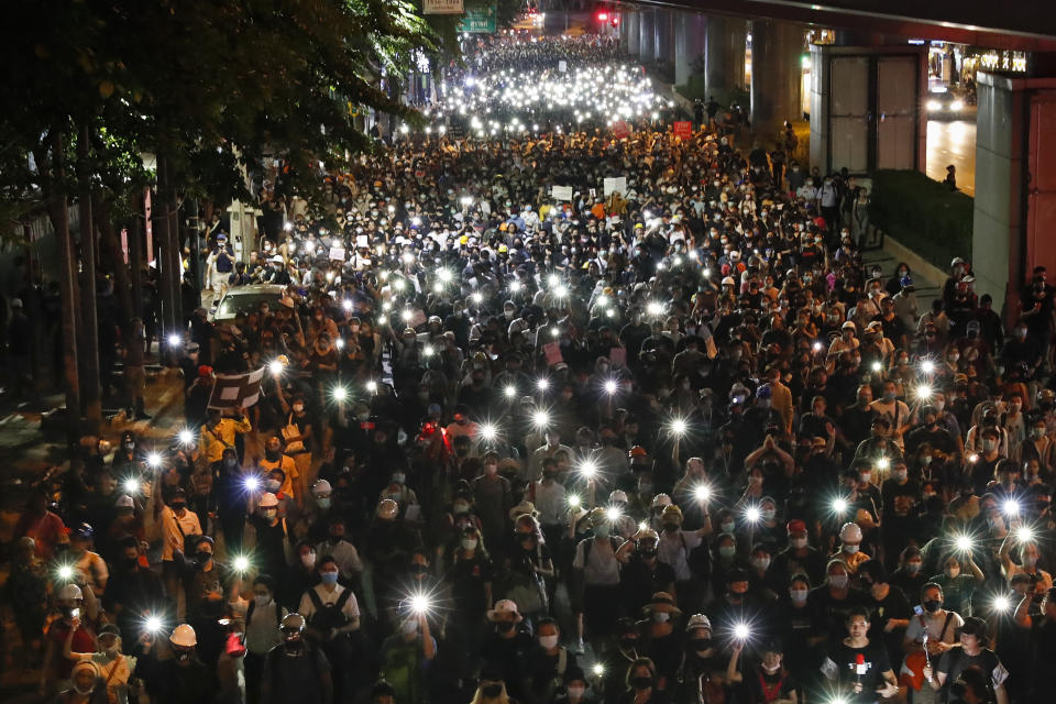 Pro-democracy demonstrators shine their mobile phone lights as they march to the German Embassy in central Bangkok, Thailand, Monday, Oct. 26, 2020. As lawmakers debated in a special session in Parliament that was called to address political tensions, student-led rallies were set to continue with a march through central Bangkok on Monday evening to the German Embassy, apparently to bring attention to the time King Maha Vajiralongkorn spends in Germany. (AP Photo/Gemunu Amarasinghe)