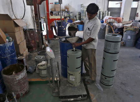 A worker fills paint in a container inside a Reliable Paints factory at an industrial area on the outskirts of Vadodara in Gujarat, India, November 5, 2015. REUTERS/Amit Dave