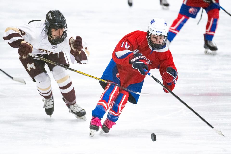 Natick freshman Jordan DiGiandomenico races with the puck down the ice, under pressure from an Algonquin/Hudson defender, during the game in Marlborough, Jan. 8, 2024. The Titans beat the Redhawks, 2-0.