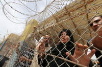 Palestinians stand behind a fence as they wait for their relatives to return to Gaza at Rafah border crossing between Egypt and southern Gaza Strip May 26, 2015. REUTERS/Ibraheem Abu Mustafa