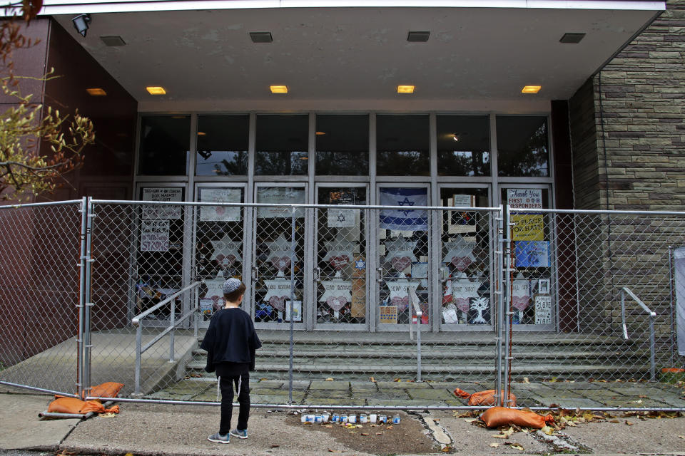 A young boy looks at the fenced off entrance to the Tree of Life synagogue in Pittsburgh on Sunday, Oct. 27, 2019, the first anniversary of the shooting at the synagogue, that killed 11 worshippers.(AP Photo/Gene J. Puskar)