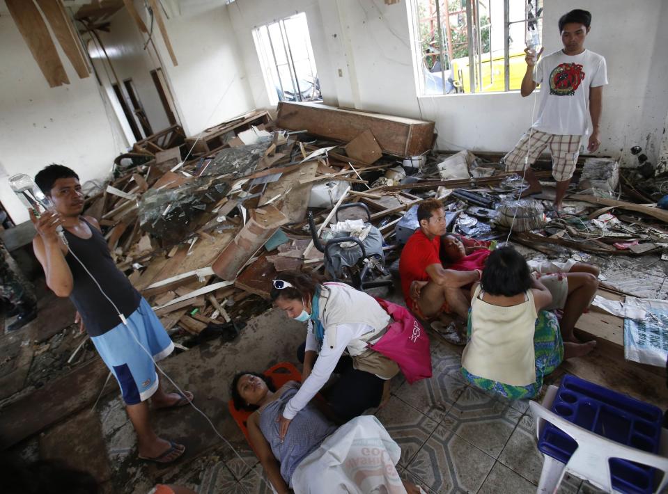 A pregnant woman and a mother who has just given birth lie inside a room that was damaged at the height of super Typhoon Haiyan in central Philippines