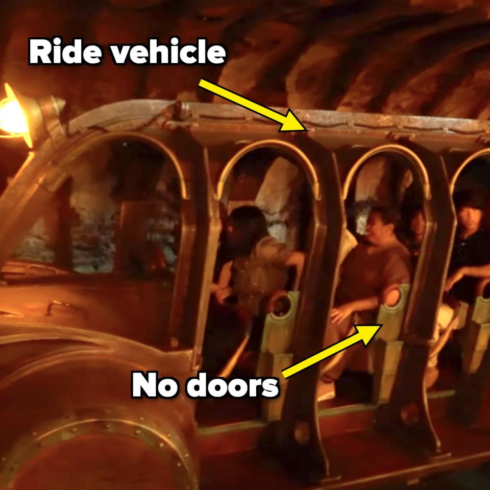 Four people ride through a themed tunnel in a metal, bus-like ride vehicle resembling a mining cart