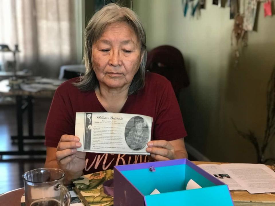 Rose Betthale-Reid holds up the obituary her family wrote for her father William, who went missing in the Petitot River in 2010. (Anna Desmarais/CBC North - image credit)