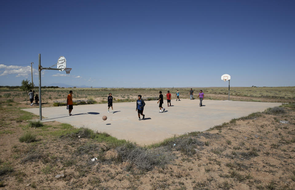 FILE - In this Sept. 25, 2014, file photo, students play basketball at Little Singer Community School in Birdsprings, Ariz., on the Navajo Nation. Basketball is woven in the fabric of Native American life. Now, during a global pandemic, the balls have all but stopped bouncing. Already hit hard by the coronavirus outbreak, Native Americans are faced with life without basketball — or any other sport - for the forseeable future. (AP Photo/John Locher, File)