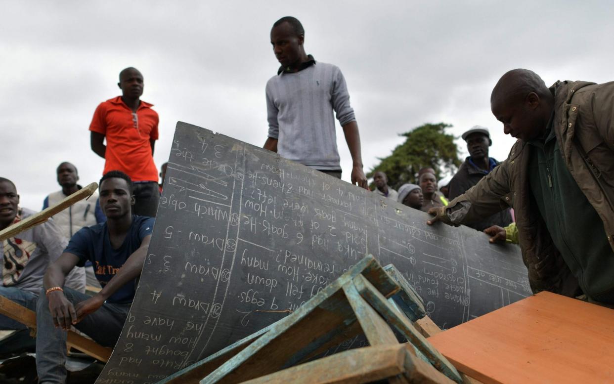 Searchers recover a tattered chalkboard from the wreckage - AFP