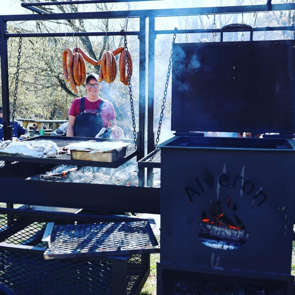 Chef Michelle Bailey cooking on an open fire on her custom wood-fired grill, "Jolene."